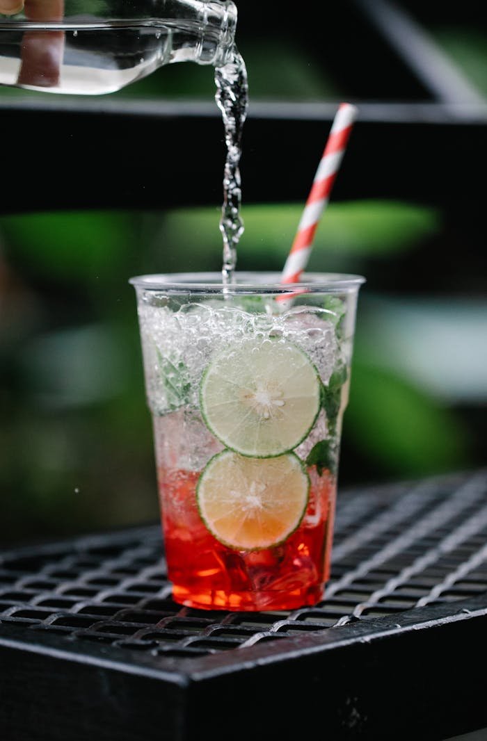 Vibrant mojito with lime and berry, captured mid-pour for a refreshing feel.