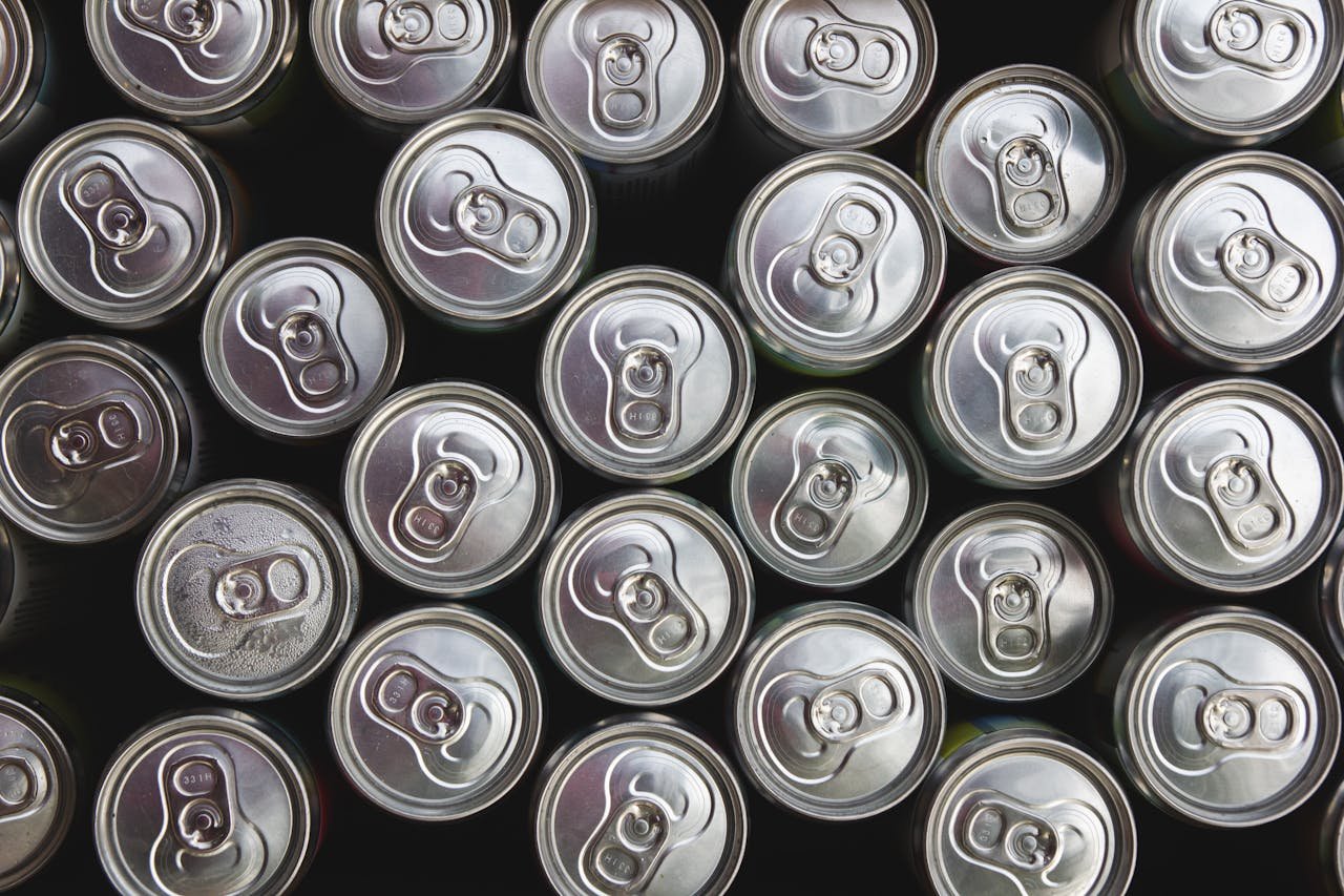Overhead photo of neatly arranged silver beverage cans, offering a metallic texture and geometric pattern.